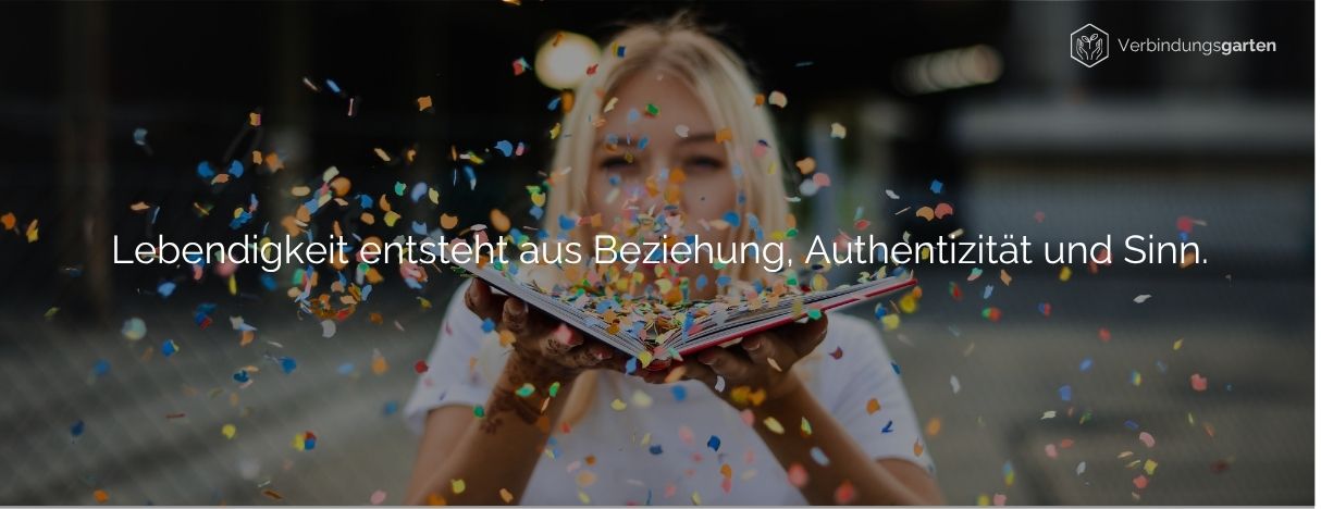 Eine blonde Frau bläst buntes Konfetti von dem aufgeschlagenen Buch in ihren Händen. Darauf steht: Lebendigkeit entsteht aus Beziehung, Authentizität und Sinn.